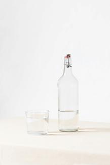 rocks glass beside half empty bottle on white surface by Laura Mitulla courtesy of Unsplash.